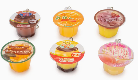 Six colorful squishy pudding jelly cup capsules with keychains in various fruit and dessert designs