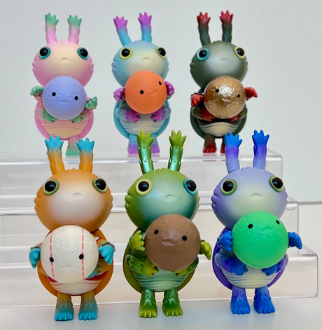 Six colorful dung beetle figurines holding balls, displayed on clear tiered stands against a white background