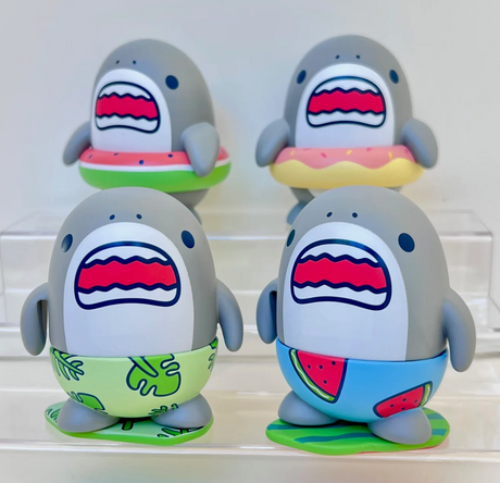 Four playful shark figurines wearing colorful summer swim trunks and floaties on a clear display stand