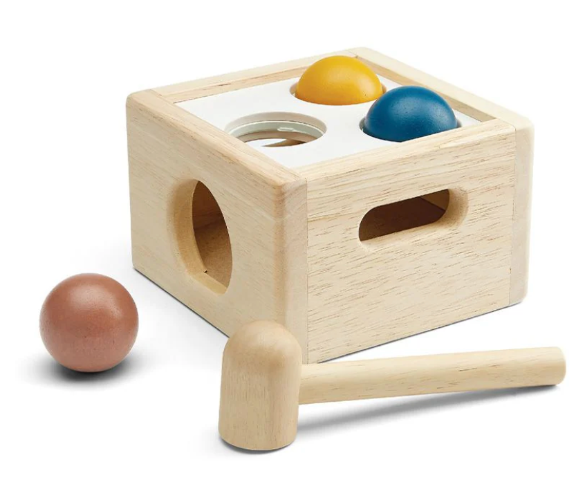 Wooden hammer toy with colorful balls and a box for pounding and dropping, designed for young children’s play.
