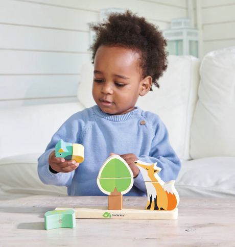 Toddler playing with Foxy Magnetic Stacker wooden puzzle pieces including fox, duck, and tree for early learning.