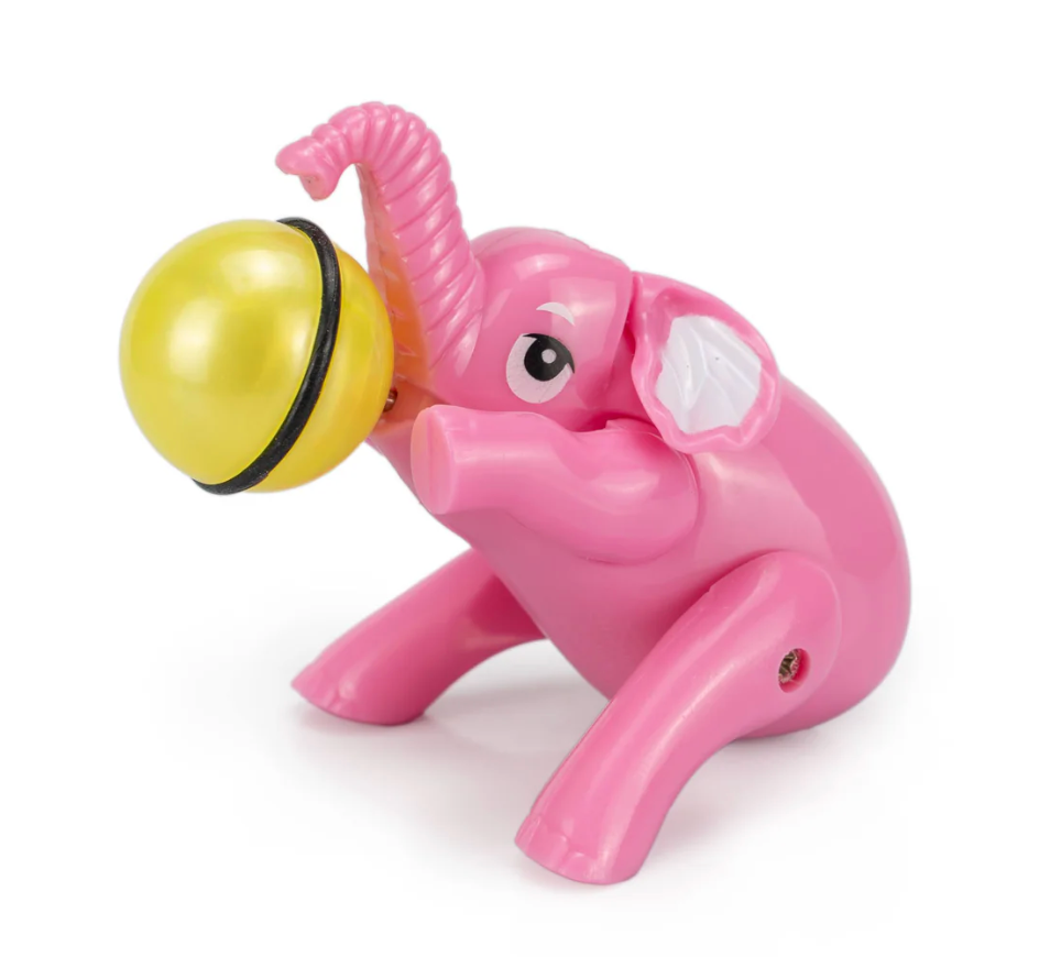 Pink toy elephant holding a yellow ball on its trunk with a playful expression and seated pose