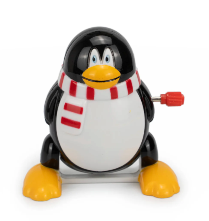 Wind-up toy penguin with a red and white scarf, smiling and ready to entertain children aged three and up.