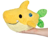 Soft yellow lemon shark plush toy with green leaf-shaped fins held in one hand against white background