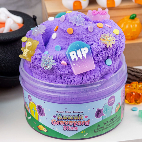 Purple cloud creme slime with colorful confetti and spooky graveyard-themed charms in clear container on table