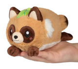 Soft plush tanuki snacker with a cute face and leaf on head held in adult hand.