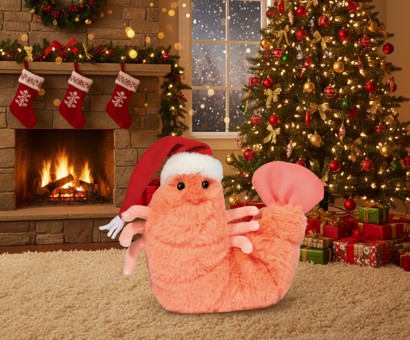 Plush shrimp toy wearing a red Santa hat with soft orange and pink textured body and twinkling black eyes
