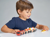 Young boy happily playing with a colorful wooden space rocket train set on a white table