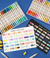 Two sets of duel tone brush tip acrylic paint markers with color swatch sheets on a blue background