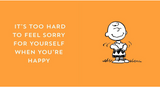 Charlie Brown smiling and dancing with the quote about happiness on an orange background.