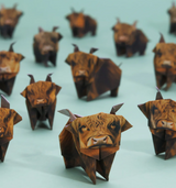 Group of handcrafted origami Highland cows made from brown patterned paper on a light blue surface