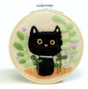 Needle felted black cat surrounded by green leaves and purple flowers in wooden embroidery hoop.
