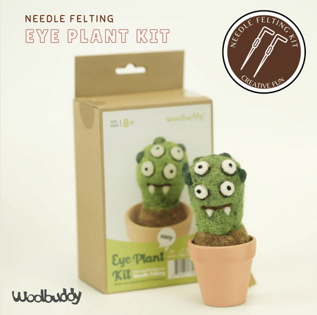 Green felted eye plant monster with multiple eyes in a small terracotta pot next to its packaging box