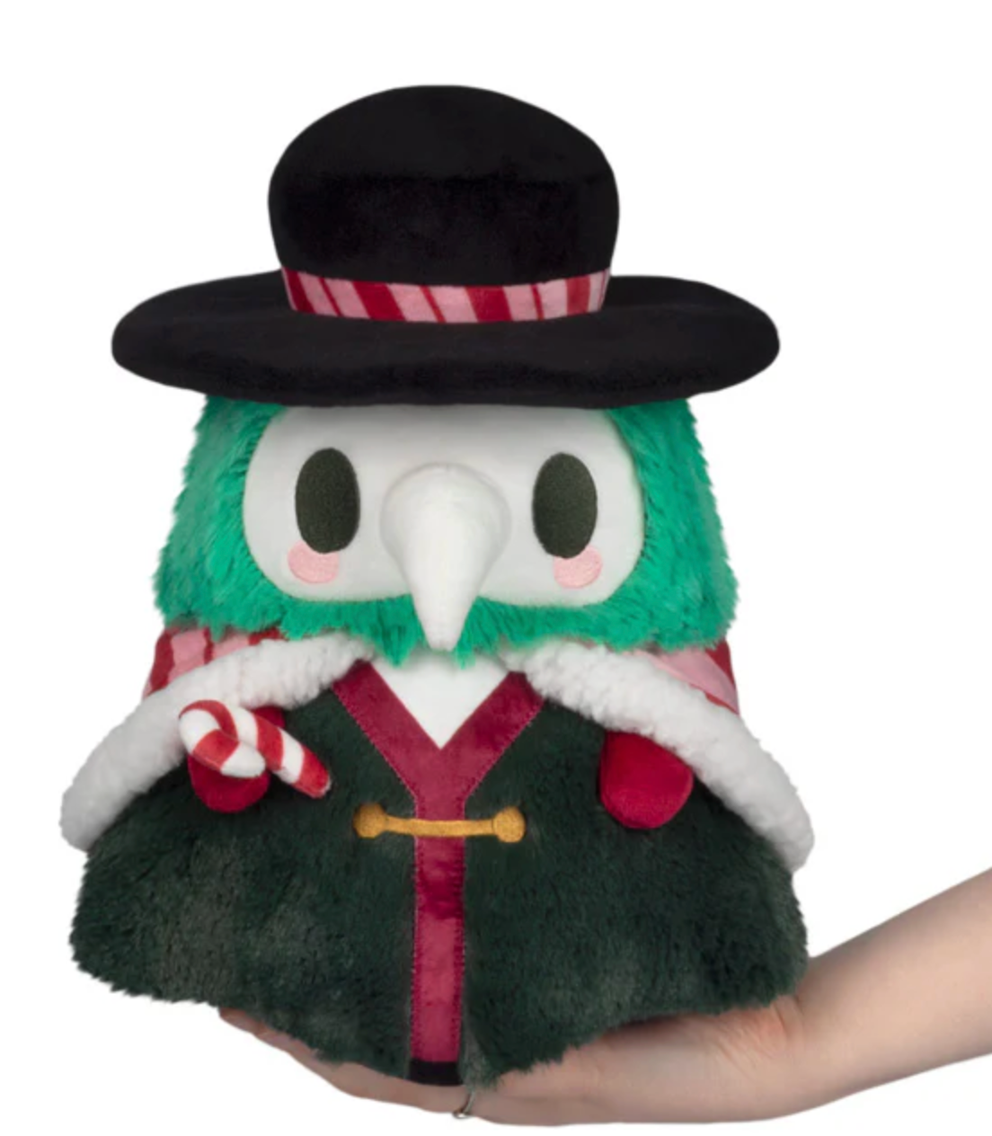 Soft plush figure with green fur, white beak mask, black wide-brimmed hat, festive cape, and striped candy cane accessory