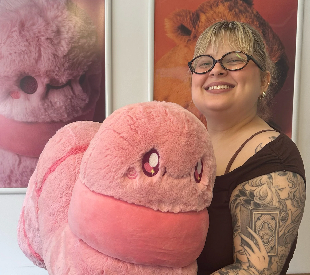 Worm Mega pink plush toy held by a smiling woman