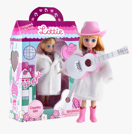 Lottie Country Girl doll in pink cowboy hat and white coat with guitar and boxed doll accessory