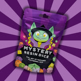 Purple package with a smiling green cat character and the words Mystery Resin Dice against a purple starburst background