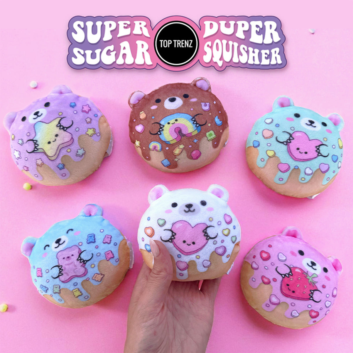Hand holding a white plush donut bear with pink heart, surrounded by colorful donut bear plush toys on pink background