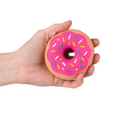 Hand holding a pink toy doughnut with colorful sprinkles against a white background