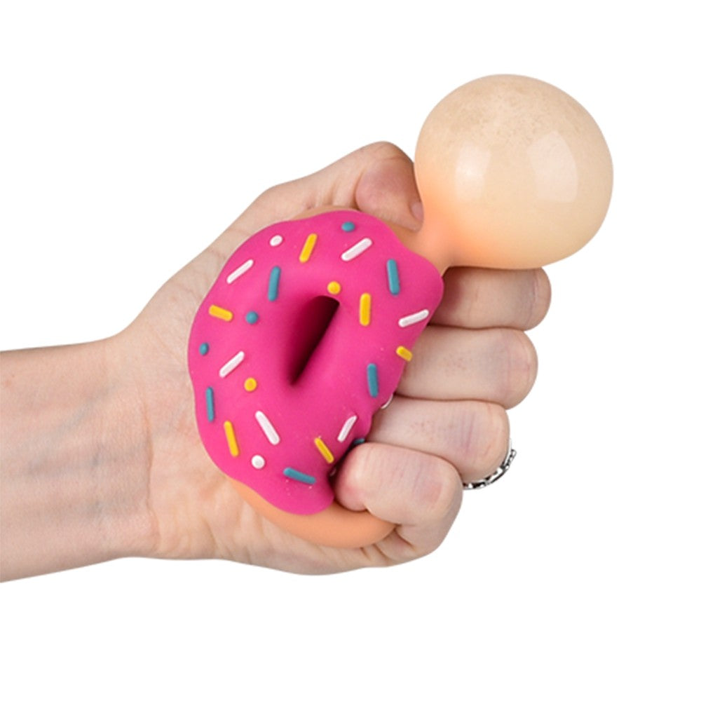 Hand holding a pink donut shaped squishy toy with colorful sprinkles and a beige round ball