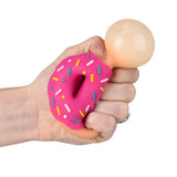 Hand holding a pink donut shaped squishy toy with colorful sprinkles and a beige round ball