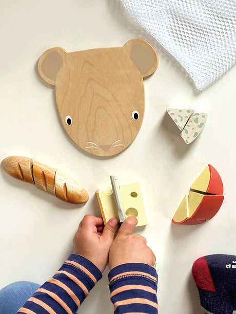 Child playing with Cheese Chopping Board set featuring wooden cheese pieces, baguette, mouse-shaped board, and knife.