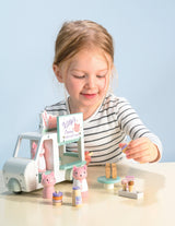Young girl playing with Kitty's Milkshake Van toy set featuring a white 3-wheeler and colorful milkshake accessories.