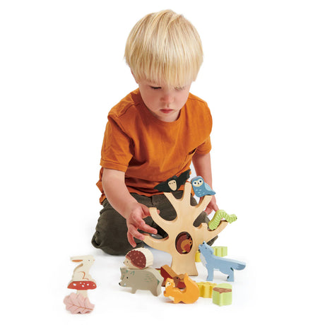 Child playing with colorful wooden animals stacking on a tree trunk in the Stacking Forest toy set.
