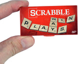 Hand holding the world's smallest Scrabble game box with letter tiles spelling "PLAYS WIN" on the cover