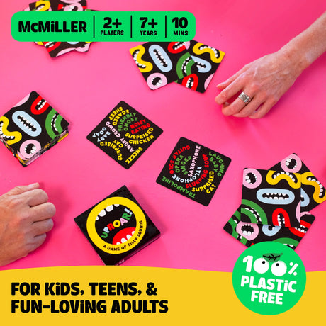 Uproar! card game laid out on pink table with players’ hands, colorful cards featuring silly words and designs.