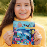 Square Sketchbook | Sea Life held by a smiling child featuring colorful dolphins sea turtles seahorses and coral