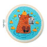 Punch needle embroidery of an orange alpaca with a pumpkin on its head on bright blue fabric background