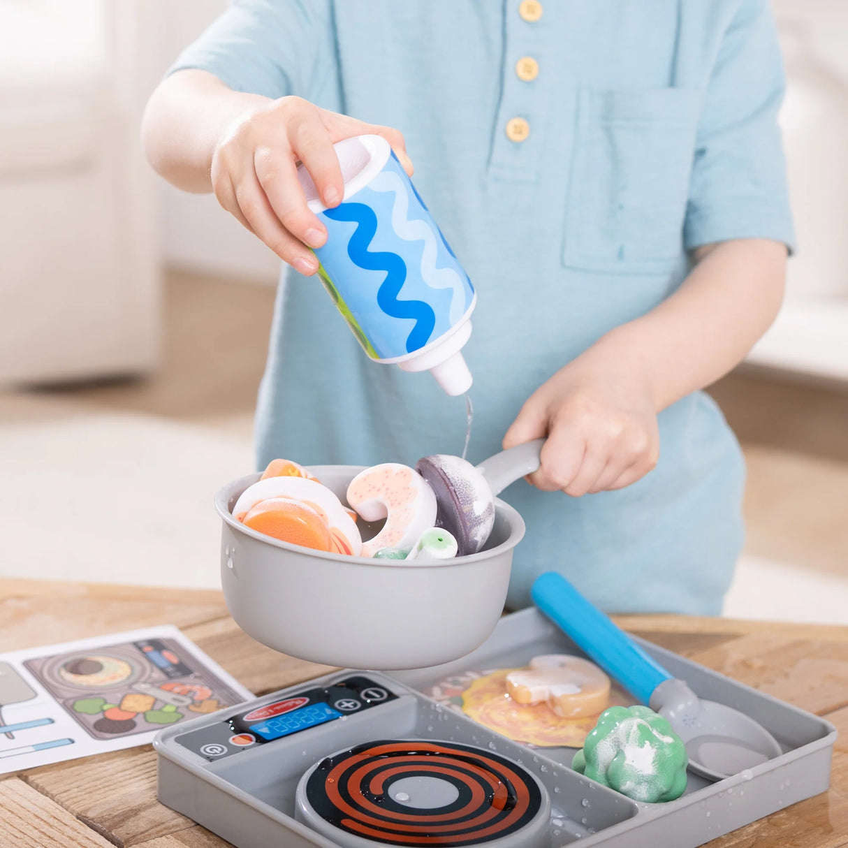 Child pretending to cook with Simmer Stir Stovetop Play Set pouring liquid onto colorful play food in pot