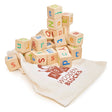 Stack of colorful wooden alphabet blocks spilling out of a cream drawstring bag labeled wooden blocks for children’s learning play