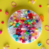 Colorful beads and charms trapped inside a PickMe Pad on a bright yellow background with scattered small objects.