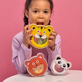 Child holding a tiger-shaped snack container with bear and panda containers on table against pink background
