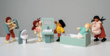 Miniature dollhouse bathroom set with bathtub, toilet, sink, and five diverse dolls playing together