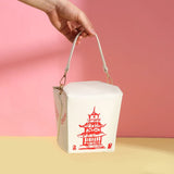 Hand holding the white Handbag | Takeout Box with red pagoda design against a pink background