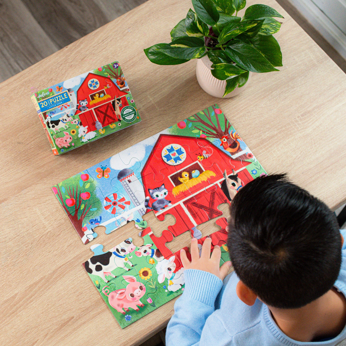 20pc Little Farm Puzzle showing a child assembling colorful farm animal pieces at a table