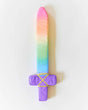 Soft fabric sword with a rainbow blade and purple handle decorated with yellow braided trim on white background