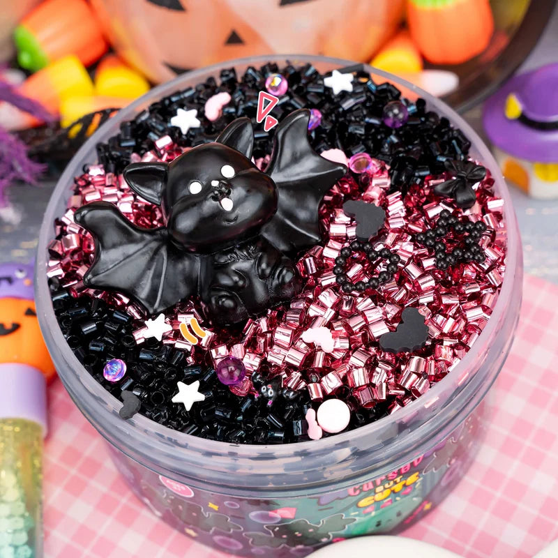 Cursed But Cute Crunchy Slime in black and pink with a bat charm and star sprinkles