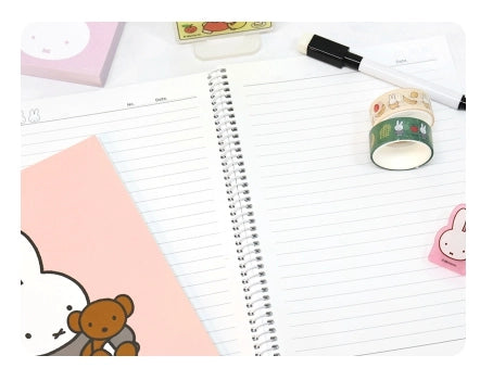 Open spiral notebook with lined pages surrounded by pastel stationery including washi tape and a pink bunny eraser