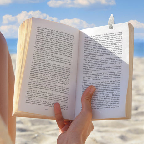 Water Marks Bookmarks featuring an open book with a feather bookmark by the beach