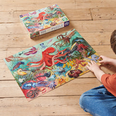 100pc Love of Octopuses & Friends Puzzle featuring a child assembling colorful sea life artwork