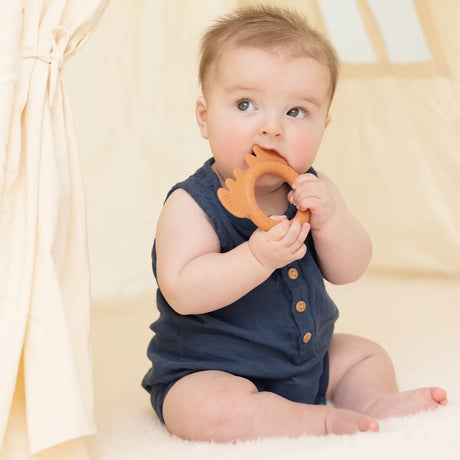 Baby chewing on a soft silicone moose-shaped teether rattle designed to soothe and engage little fingers and mouths.
