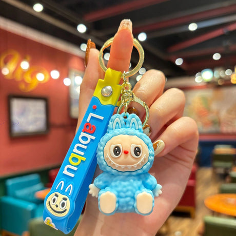 Labubu Silicone Keychain featuring a cute blue character and colorful silicone strap held in hand against a blurred background.