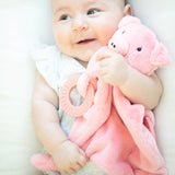 Baby holding a soft pink pig teether buddy with silicone teething ring and cuddly plush fabric