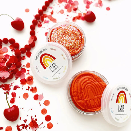KidDough Glitter | Red sensory dough with cherry bomb color and sparkle in clear containers with confetti and cherries.