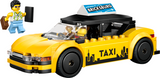 Yellow toy taxi cab model with black roof sign and minifigure holding a suitcase for pretend play set