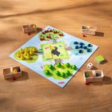 Colorful fruit pieces and baskets set on a game board featuring a raven, ready for cooperative play in Orchard Game.